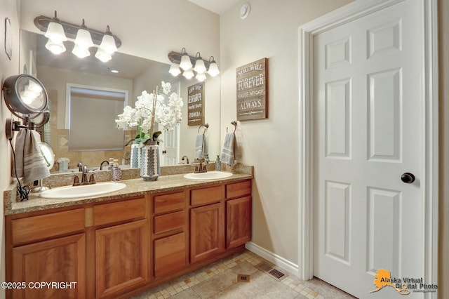 bathroom featuring baseboards, double vanity, a sink, and tile patterned floors