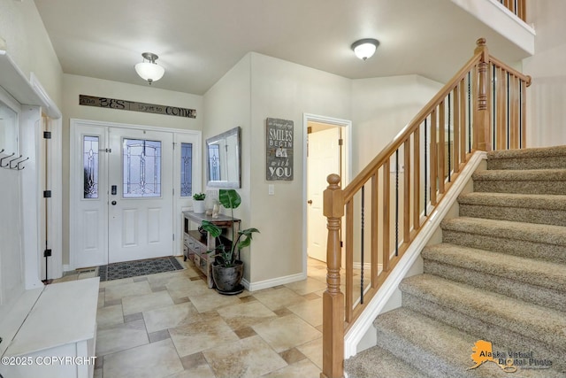 foyer entrance with stairs and baseboards