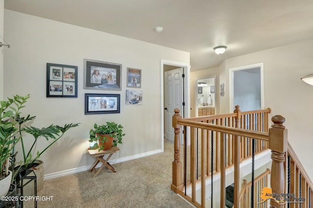 hall featuring baseboards, carpet flooring, and an upstairs landing