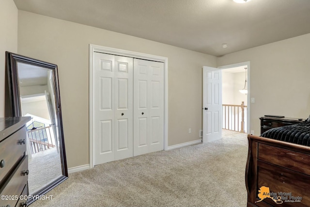 bedroom featuring a closet, light colored carpet, and baseboards