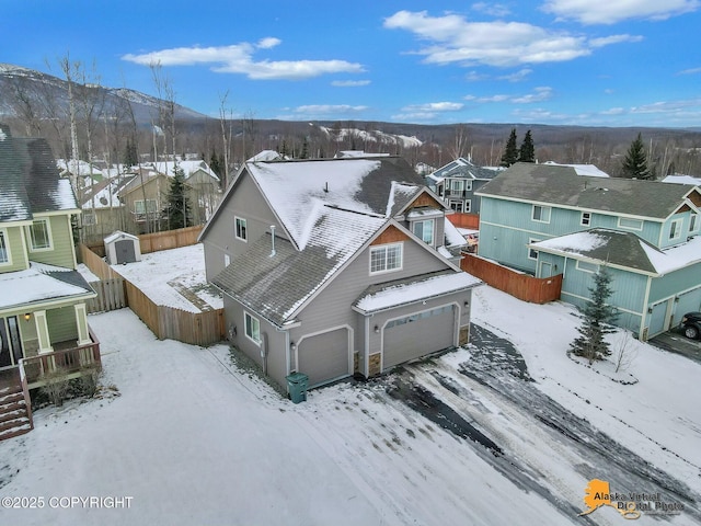 snowy aerial view featuring a residential view and a mountain view