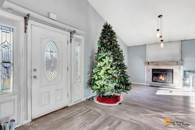 entrance foyer with vaulted ceiling, wood finished floors, a high end fireplace, and baseboards