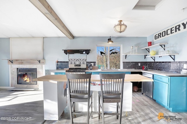 kitchen featuring open shelves, blue cabinetry, a breakfast bar area, and stainless steel appliances