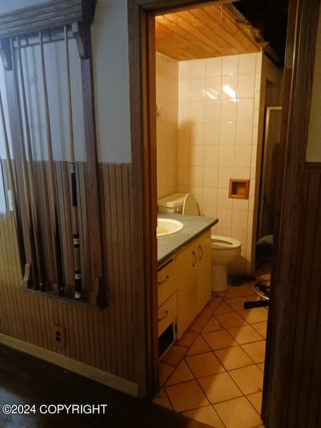 bathroom with tile walls, vanity, toilet, and tile patterned floors