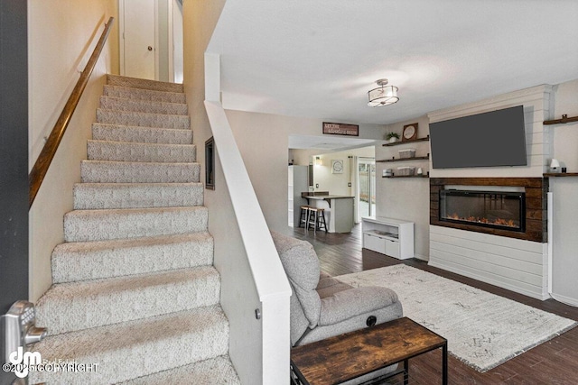 stairway featuring wood finished floors and a glass covered fireplace