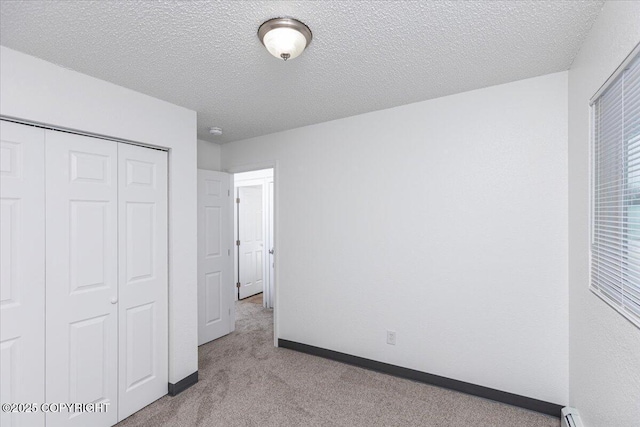 unfurnished bedroom with a closet, light carpet, a textured ceiling, and baseboards