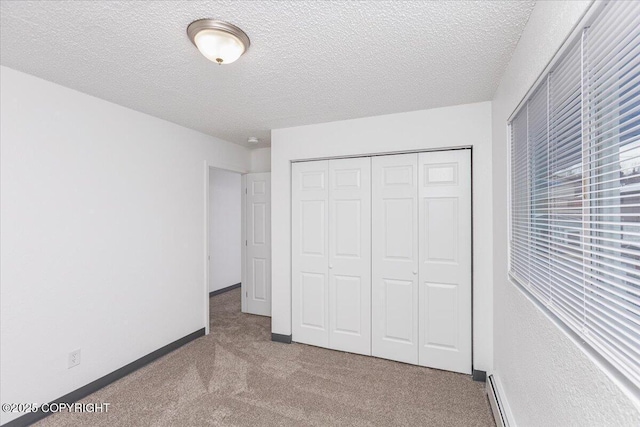 unfurnished bedroom featuring carpet floors, a closet, a textured ceiling, and baseboards