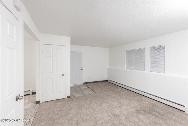 empty room with a baseboard heating unit, light carpet, and a textured ceiling