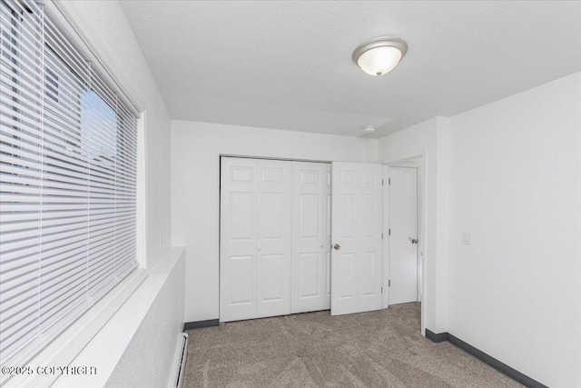 unfurnished bedroom featuring carpet, a closet, a textured ceiling, and baseboards