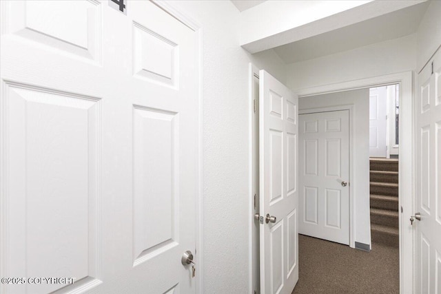 hallway with dark colored carpet