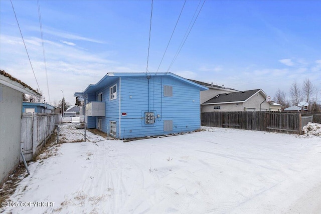 snow covered house with a fenced backyard