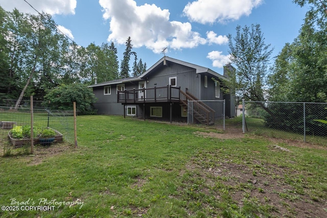 back of property with a vegetable garden, a lawn, stairway, fence, and a wooden deck