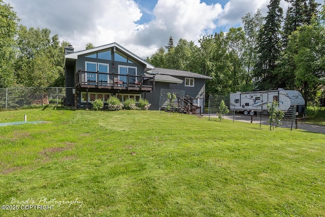 back of property featuring a deck, fence, stairway, a lawn, and a chimney