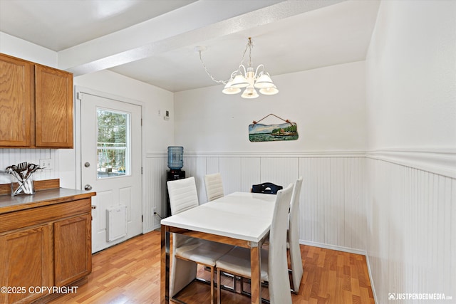 dining area featuring wainscoting, light wood-style flooring, and an inviting chandelier