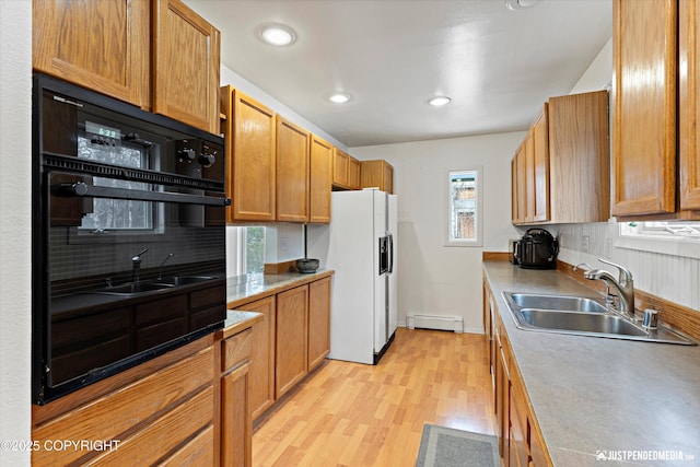 kitchen with white refrigerator with ice dispenser, light countertops, baseboard heating, a sink, and oven