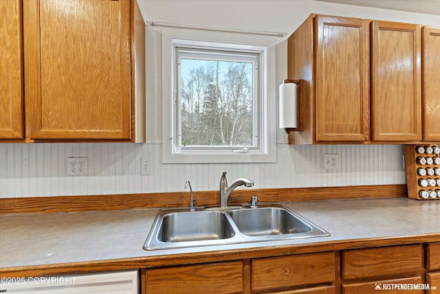 kitchen featuring brown cabinets, light countertops, and a sink