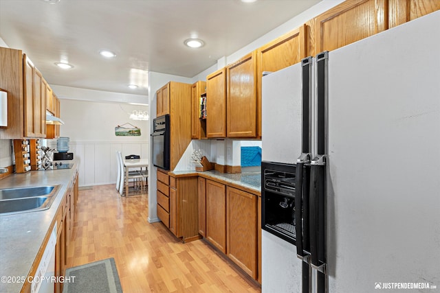 kitchen featuring light countertops, light wood-style floors, a sink, refrigerator with ice dispenser, and oven