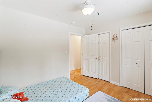 bedroom with multiple closets, baseboards, and wood finished floors