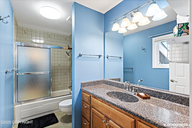 bathroom featuring enclosed tub / shower combo, visible vents, vanity, and toilet