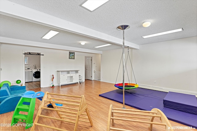 playroom featuring washer and dryer, a textured ceiling, and wood finished floors