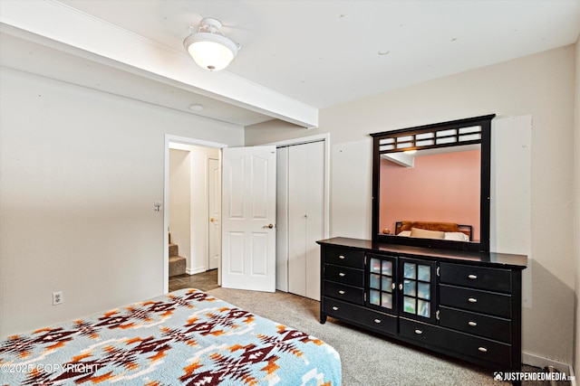 carpeted bedroom featuring a closet and beam ceiling