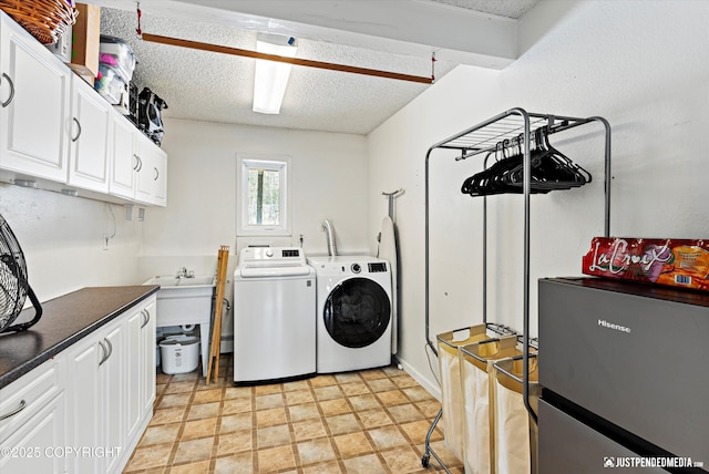 laundry room with a textured ceiling, washing machine and dryer, and cabinet space