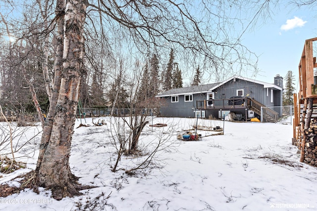 snow covered property with stairway and a deck