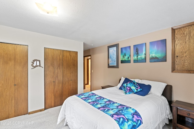 carpeted bedroom featuring a textured ceiling, baseboards, and multiple closets