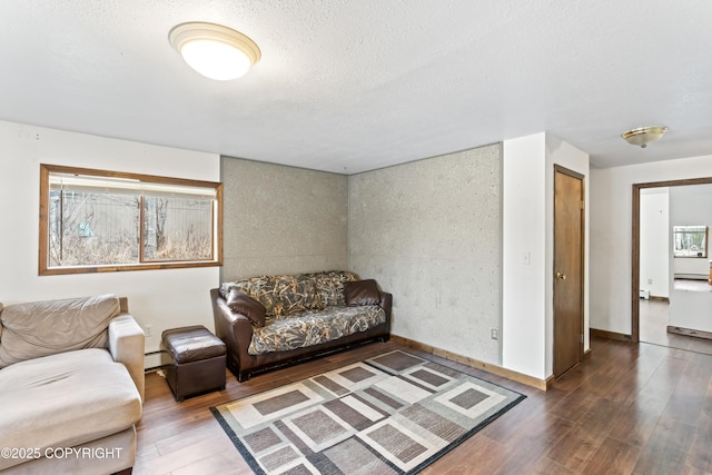 living room with dark wood-type flooring, a baseboard heating unit, a textured ceiling, and baseboards