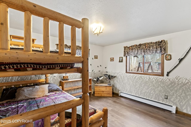 bedroom featuring wallpapered walls, baseboards, wood finished floors, a textured ceiling, and a baseboard heating unit