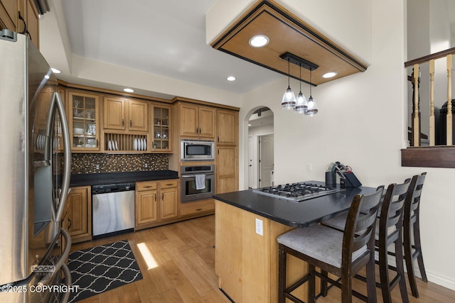 1968 S Paddock Dr, Wasilla, AK 99654 - kitchen with appliances with stainless steel finishes, a peninsula, dark countertops, brown cabinetry, and tasteful backsplash