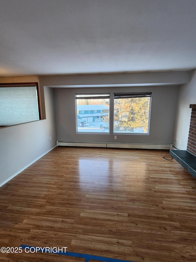 empty room with a wealth of natural light, hardwood / wood-style flooring, and a fireplace