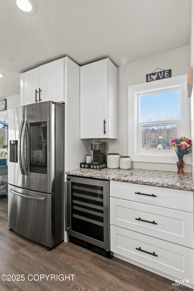 kitchen featuring stainless steel fridge, light stone counters, beverage cooler, and dark wood finished floors