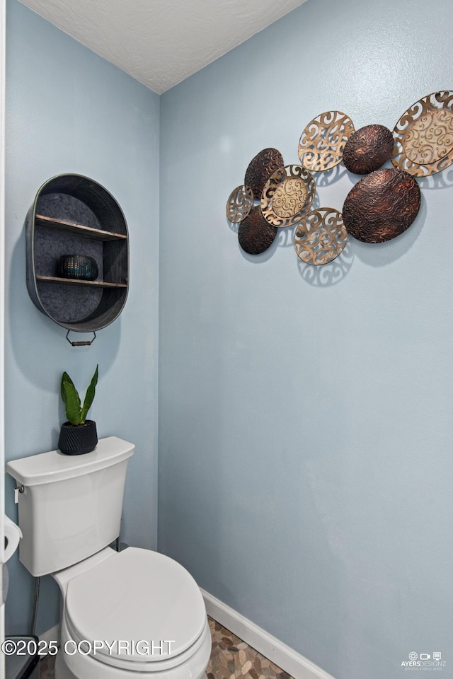 bathroom featuring toilet, baseboards, and a textured ceiling