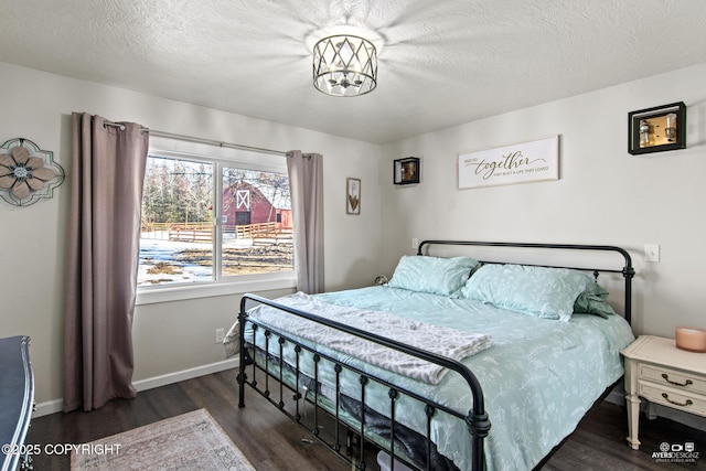 bedroom with a textured ceiling, wood finished floors, and baseboards