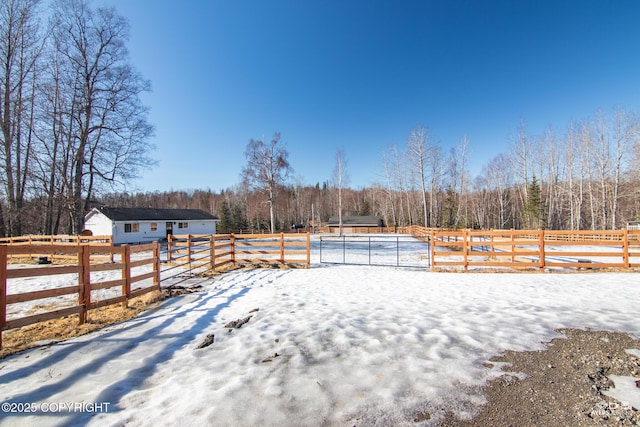 snowy yard with an outdoor structure, a view of trees, and fence