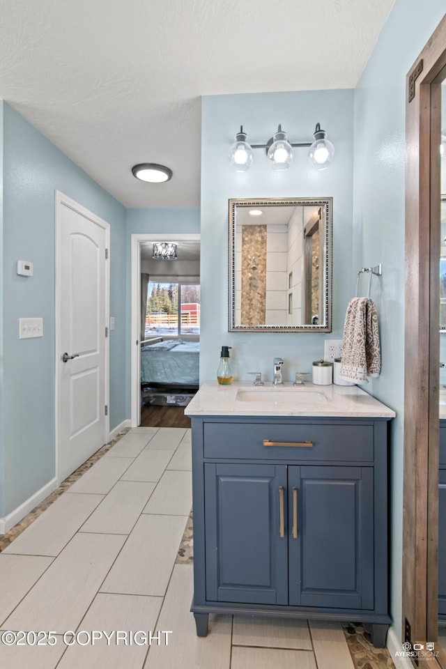 bathroom with baseboards, tile patterned floors, ensuite bathroom, a textured ceiling, and vanity