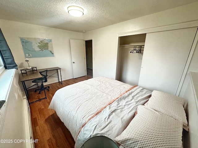 bedroom with a closet, a textured ceiling, and dark wood-style flooring