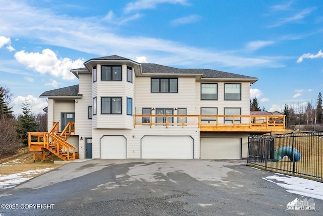 view of front of property featuring aphalt driveway, a shingled roof, an attached garage, and fence