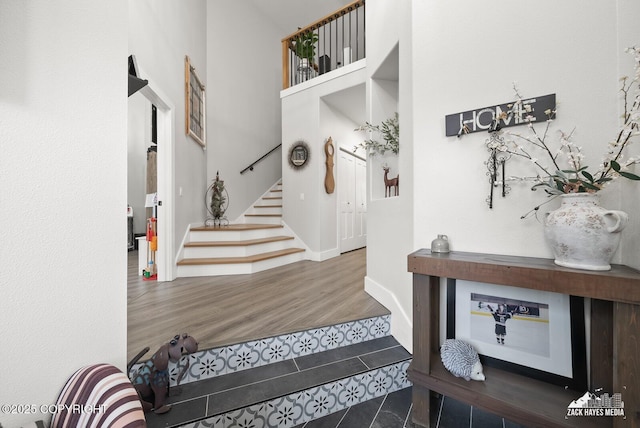 entryway featuring stairway, wood finished floors, baseboards, and a towering ceiling