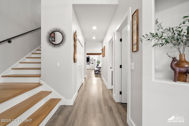 hallway with stairway, baseboards, and wood finished floors