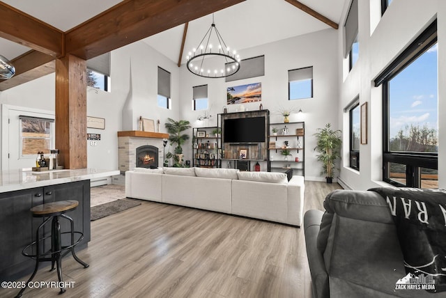 living area with beamed ceiling, a notable chandelier, a high ceiling, and wood finished floors