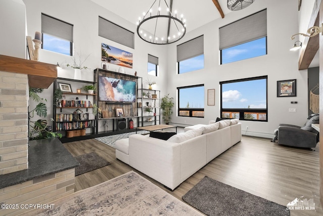 living room featuring plenty of natural light, a towering ceiling, an inviting chandelier, and wood finished floors