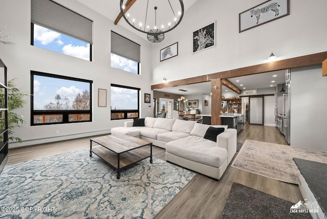 living room featuring a high ceiling, light wood-style floors, an inviting chandelier, and a baseboard radiator