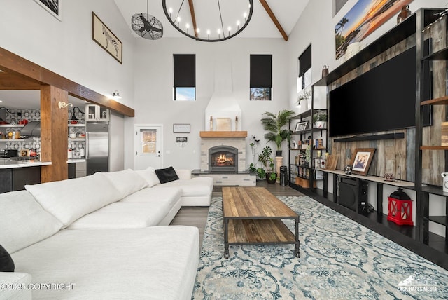 living area featuring a notable chandelier, a high ceiling, and a lit fireplace