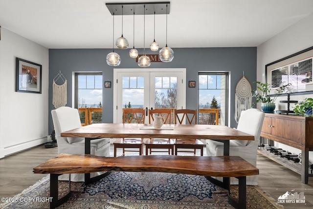 dining room featuring wood finished floors, french doors, baseboard heating, and a healthy amount of sunlight