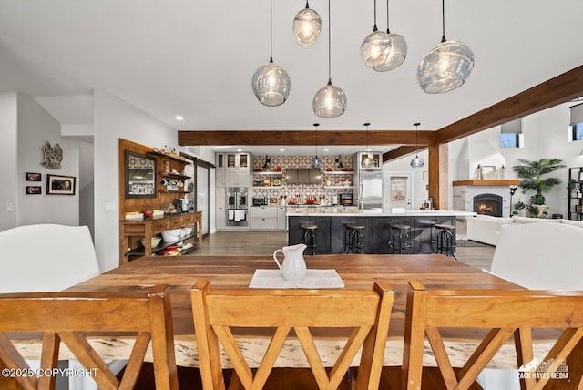 dining space featuring beamed ceiling and a lit fireplace