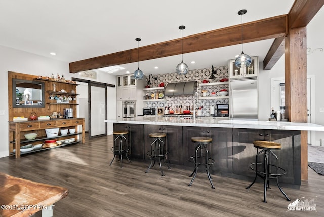 bar with beam ceiling, dark wood-style floors, appliances with stainless steel finishes, and a barn door