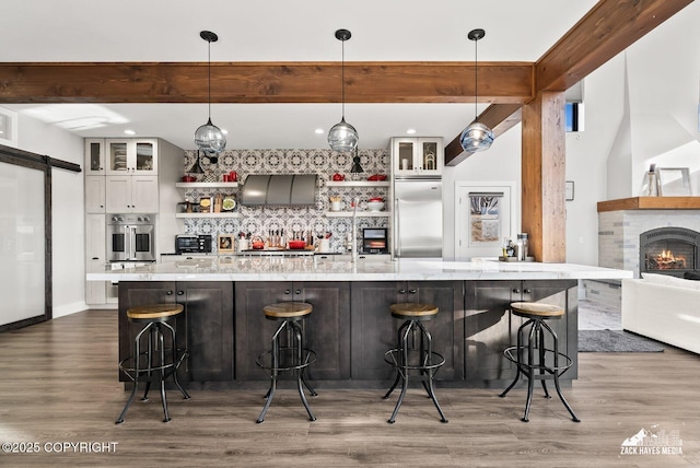 kitchen featuring beamed ceiling, appliances with stainless steel finishes, wood finished floors, and open shelves