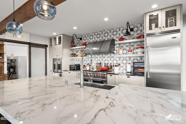 kitchen with custom range hood, open shelves, stainless steel appliances, a barn door, and light stone countertops